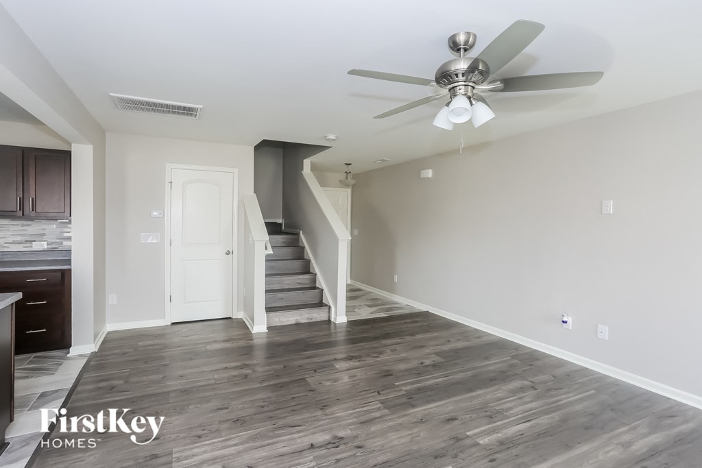 a living room with white walls and a ceiling fan