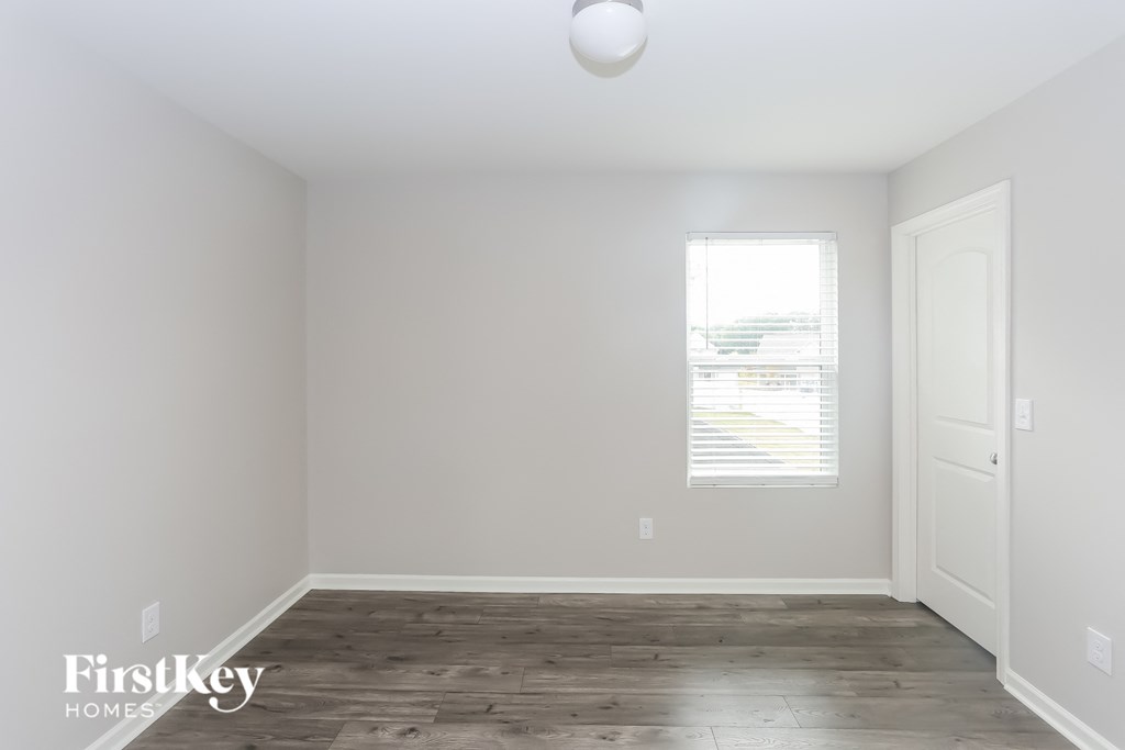 a room with white walls and wood floors and a window