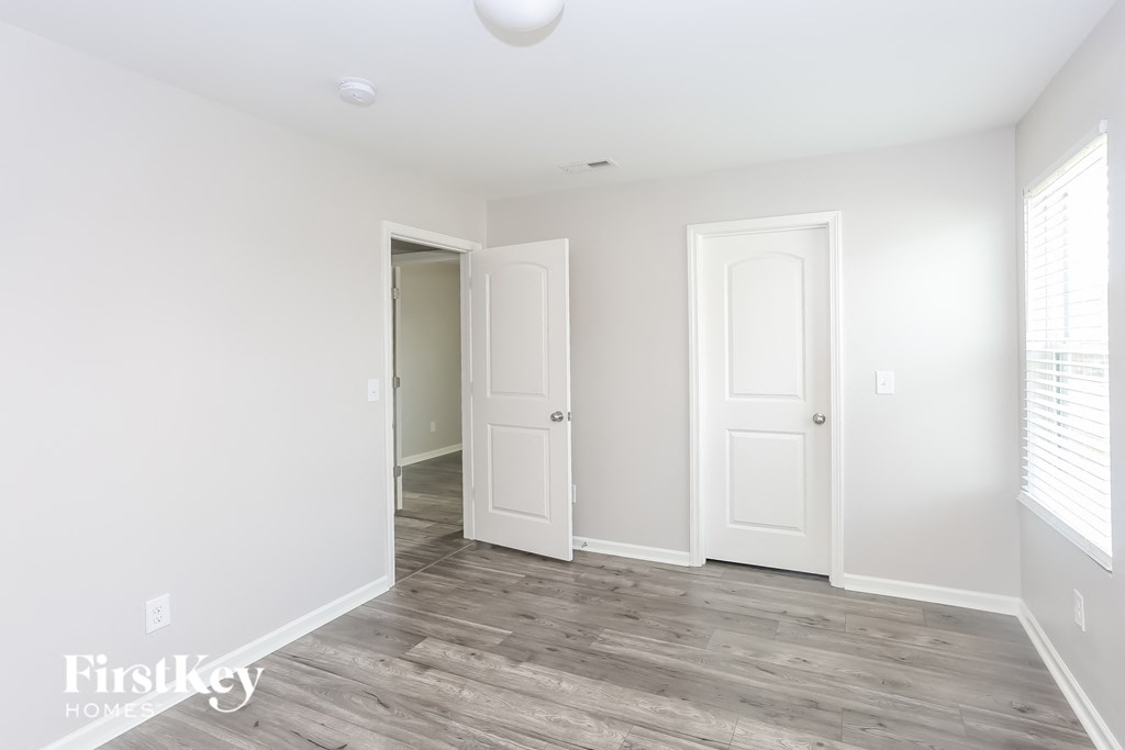 a bedroom with white walls and white doors and wood flooring