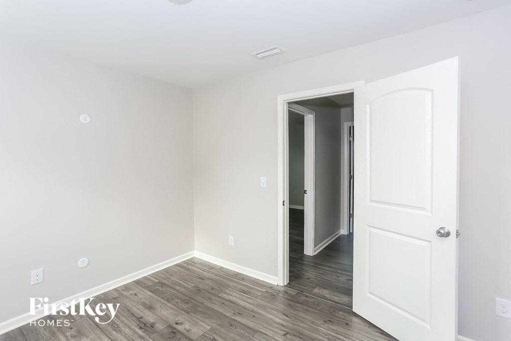 a bedroom with white walls and wood flooring and a white door