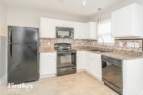 A kitchen with a black fridge, stove, and oven.