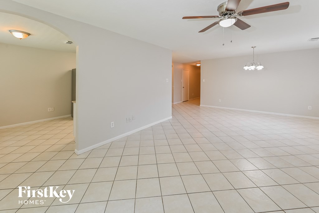an empty living room with a ceiling fan and tiled floor