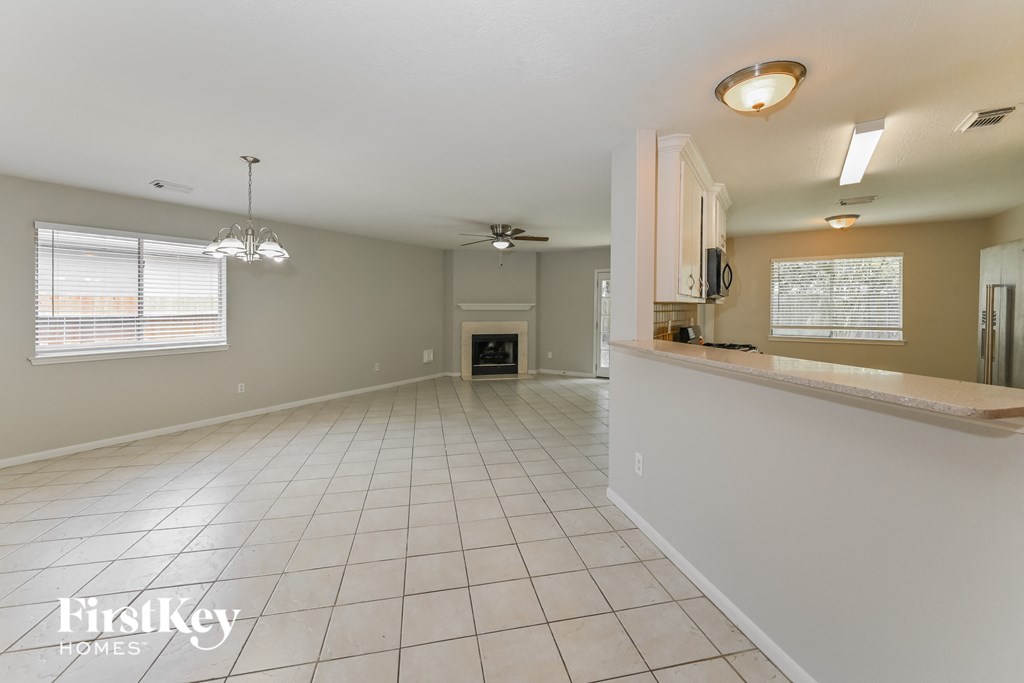 an empty kitchen and living room with tile flooring and a fireplace