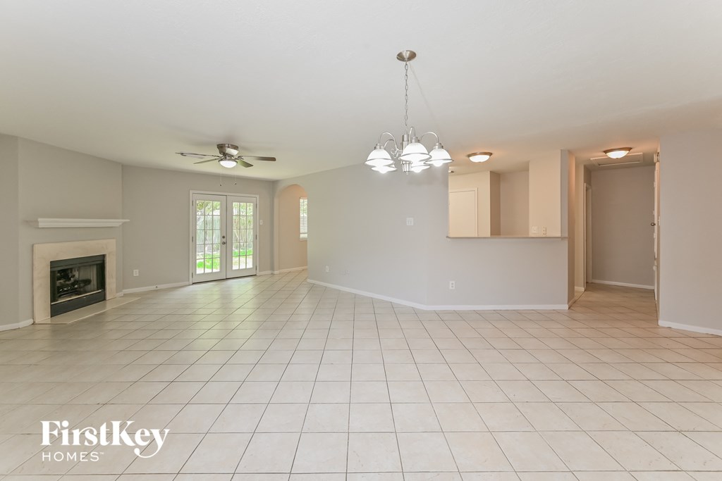 an empty living room with a fireplace and a ceiling fan