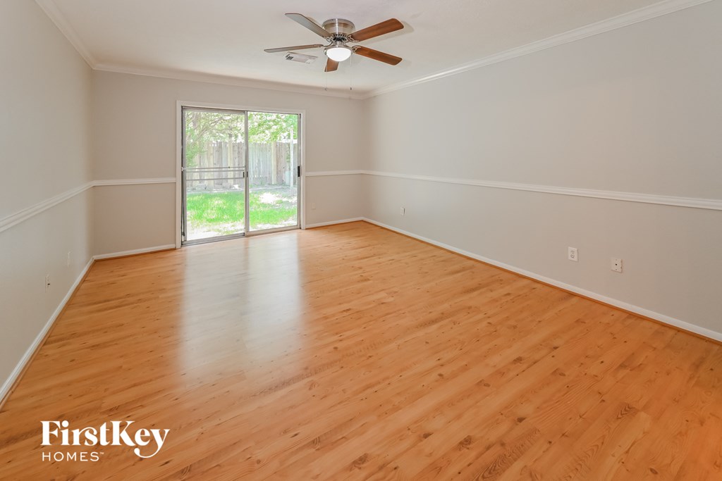 an empty living room with wood floors and a ceiling fan