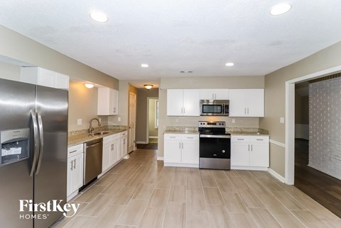A kitchen with a refrigerator and a stove top oven.