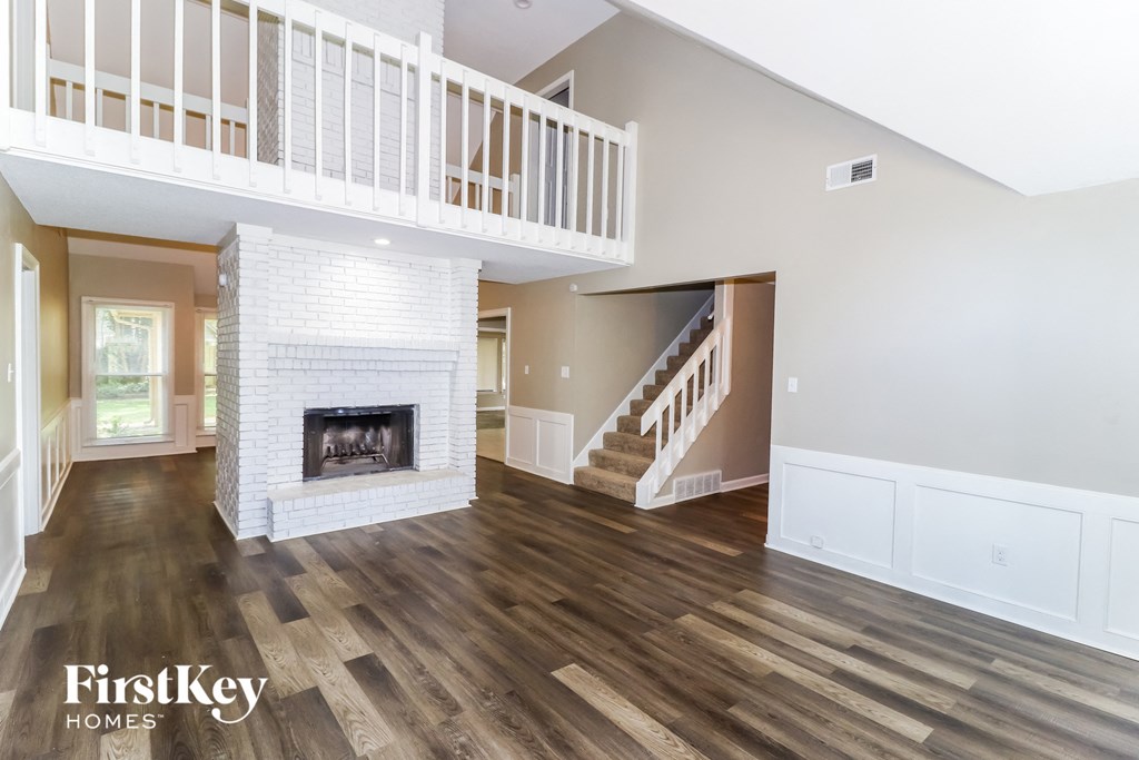 A spacious living room with a fireplace and a staircase.