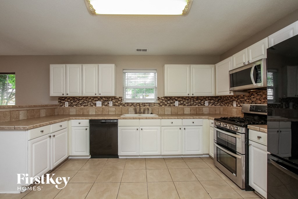 a kitchen with white cabinets and granite counter tops