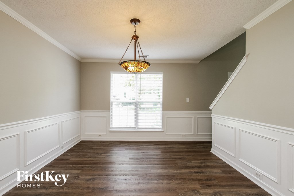 a dining room with white wainscoting and a chandelier