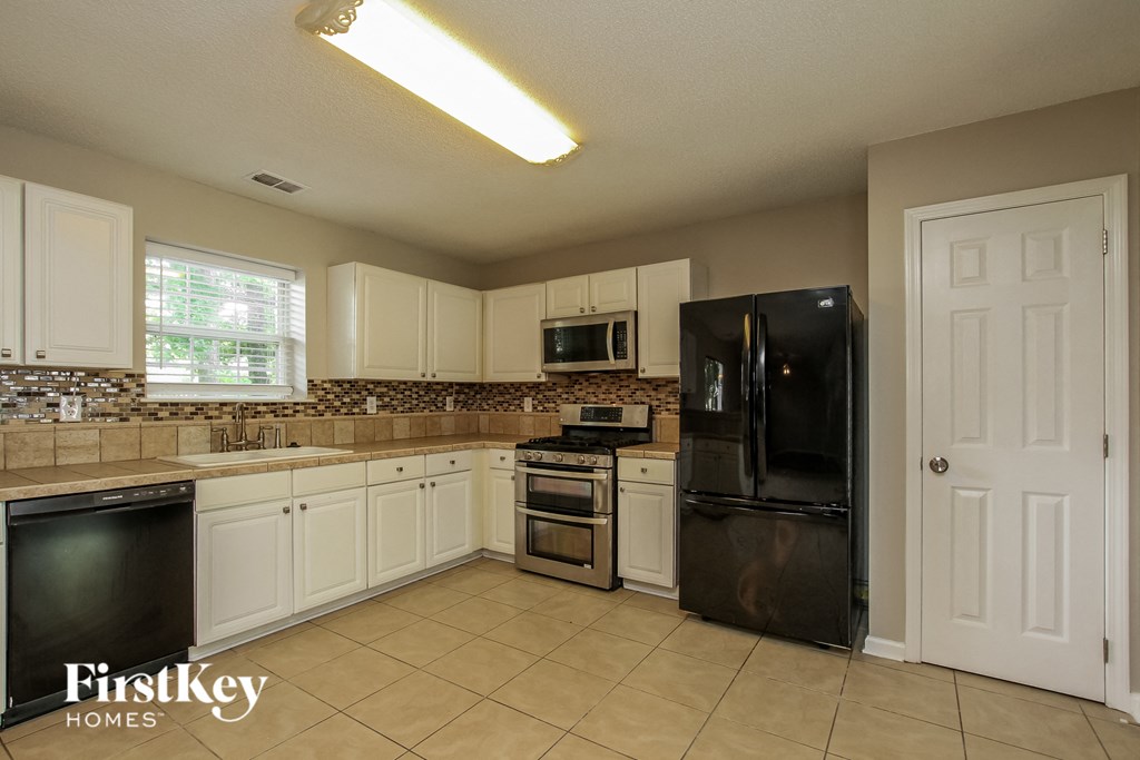 a kitchen with white cabinets and a black refrigerator