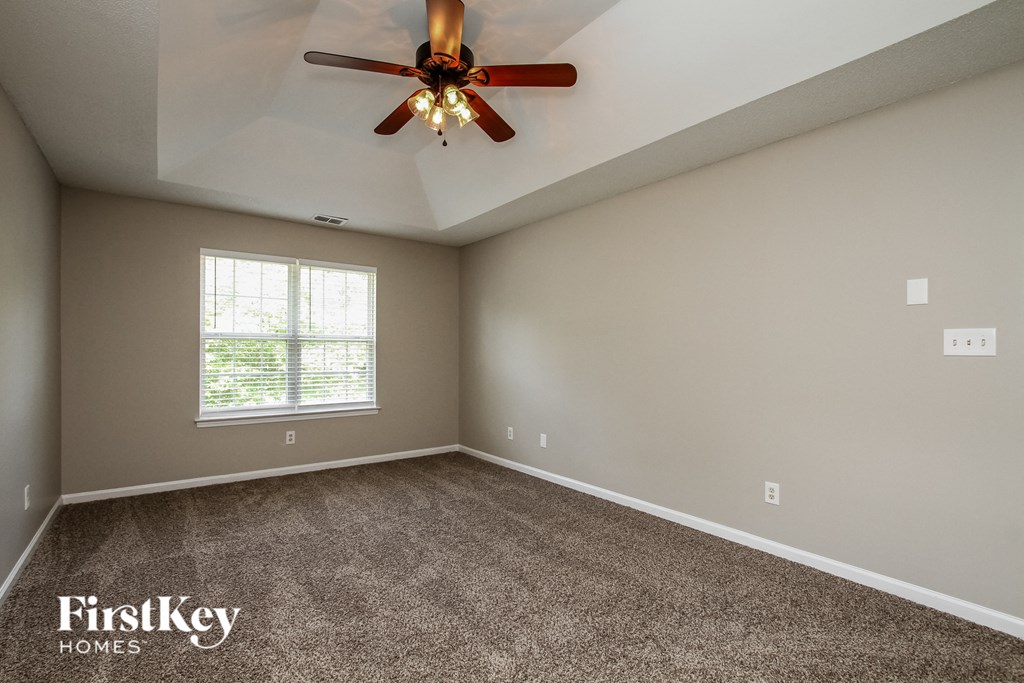 the master bedroom has a carpeted floor and a ceiling fan