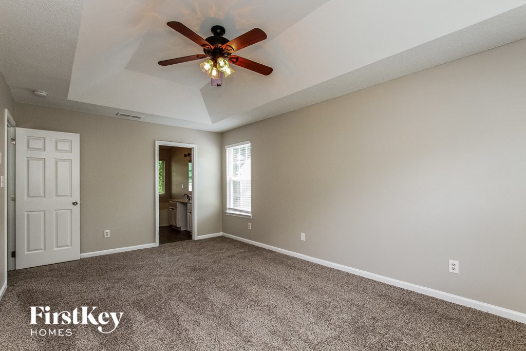 a master bedroom with carpet and a ceiling fan