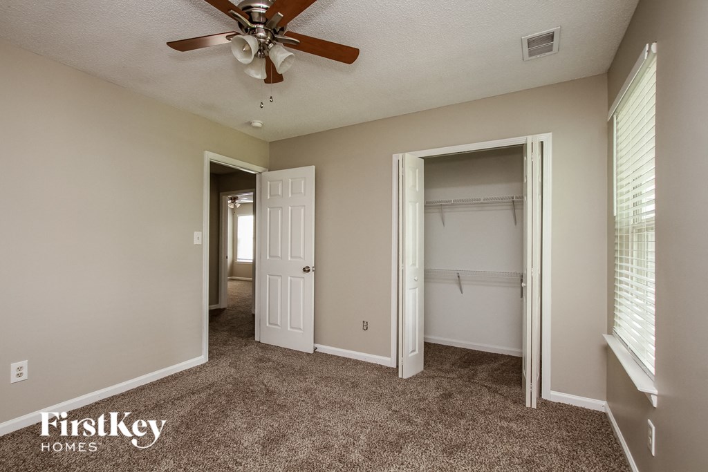 a bedroom with a ceiling fan and a closet