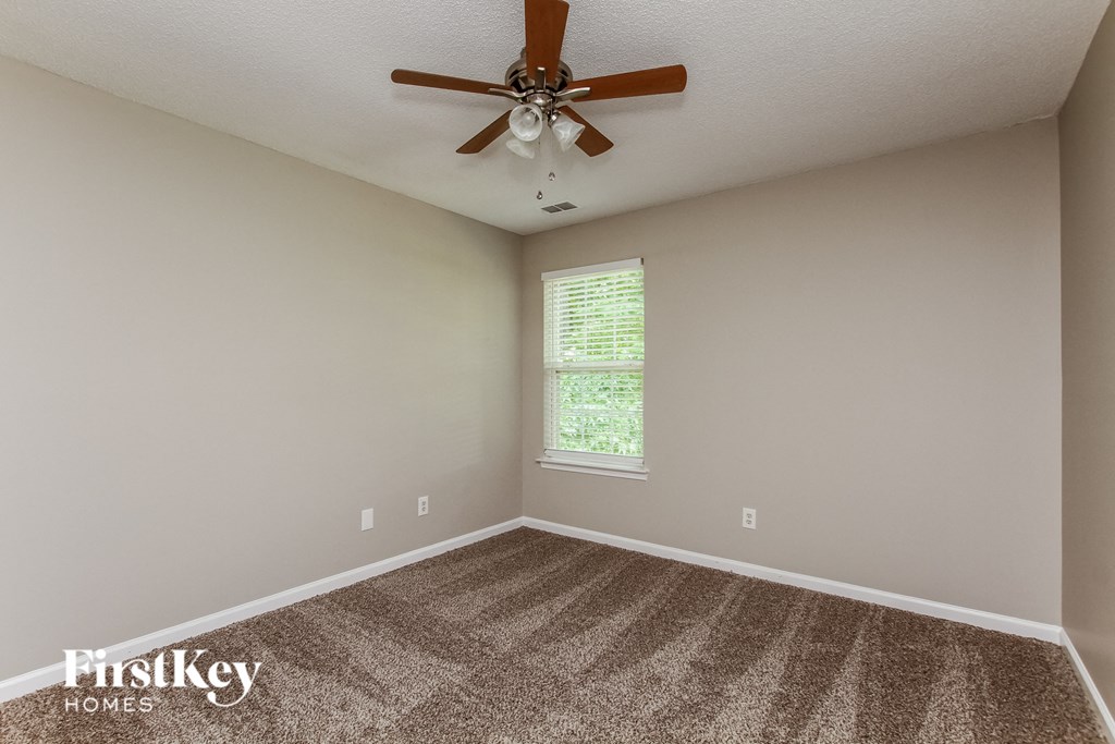 an empty room with carpet and a ceiling fan