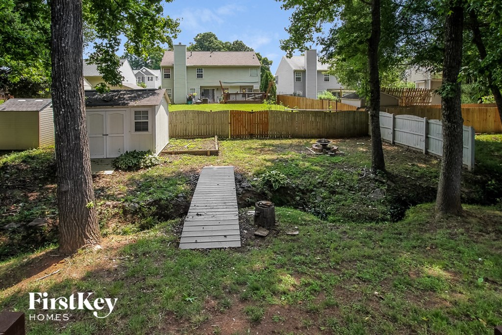 a backyard with a wooden walkway and a fence
