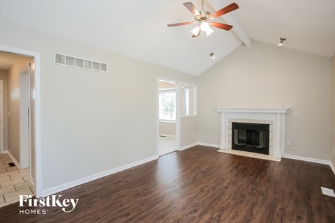 A spacious living room with a fireplace and a ceiling fan.