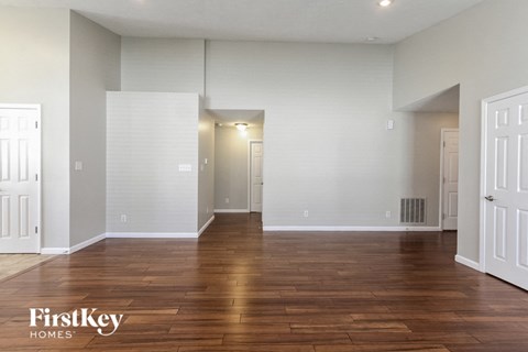 an empty living room with wood floors and white walls