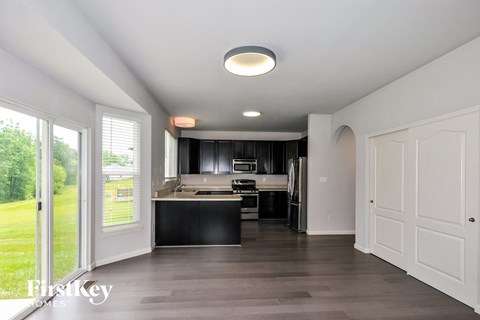 a kitchen with black cabinets and white appliances and a sliding glass door