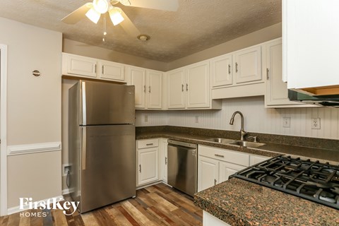 A kitchen with a stainless steel refrigerator and a granite countertop.