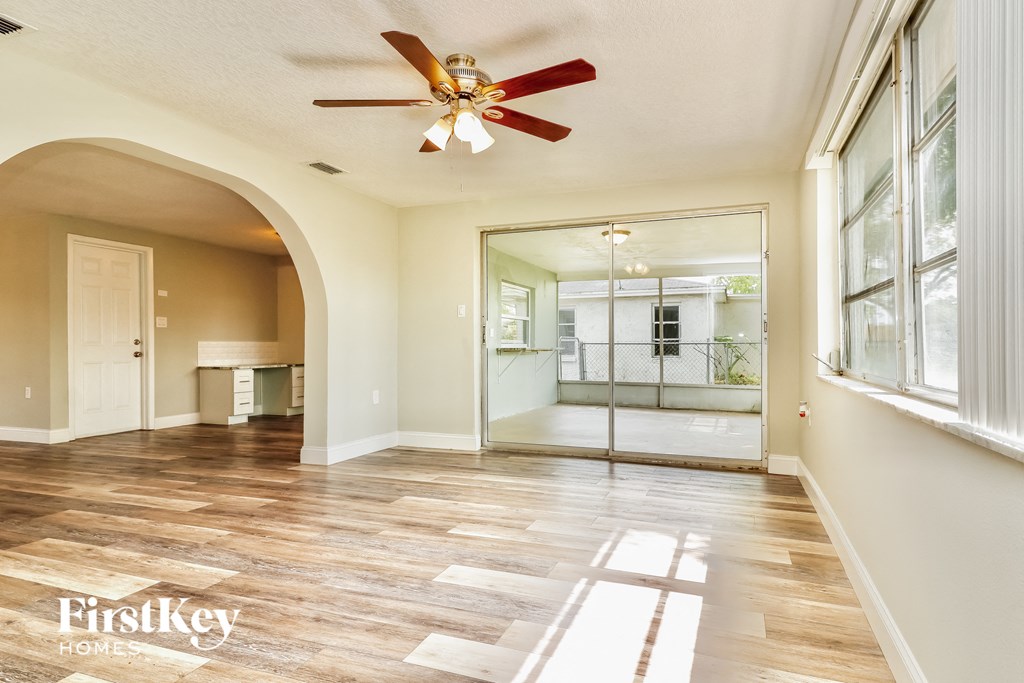 A spacious room with a fan and wooden flooring.