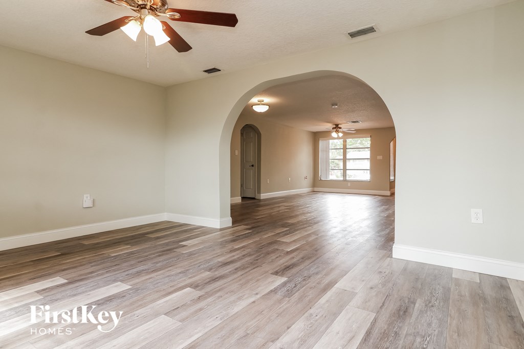 A spacious room with a ceiling fan and wooden flooring.