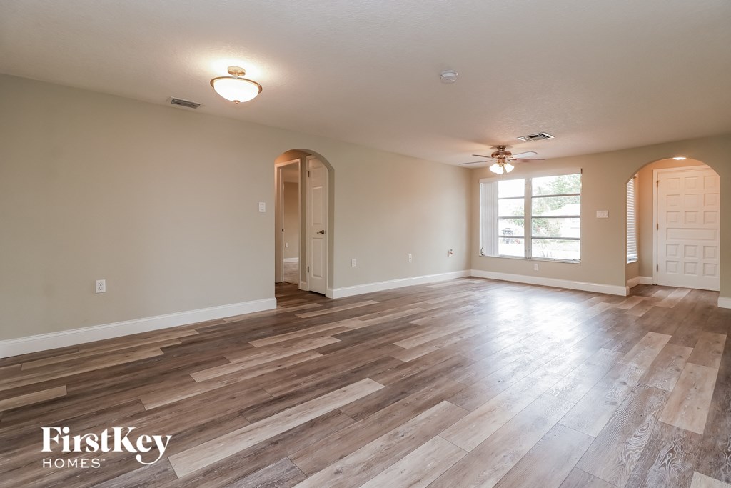 A spacious room with wooden flooring and a ceiling fan.