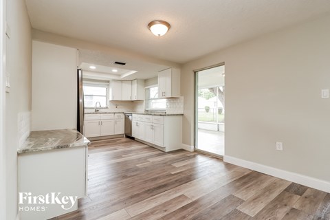 A kitchen with white cabinets and a wooden floor.