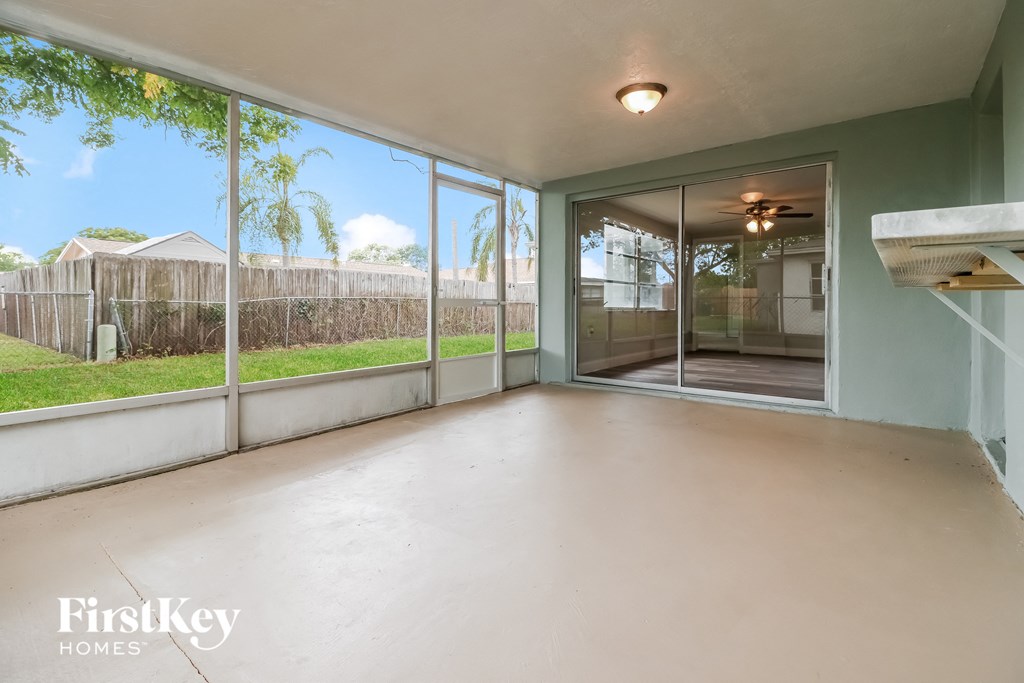 A large empty room with a view of a fence and trees outside.