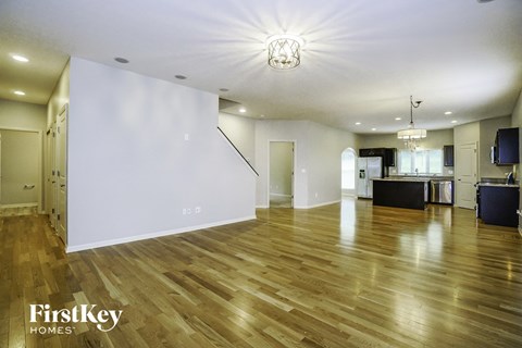 an empty living room with a hard wood floor and white walls