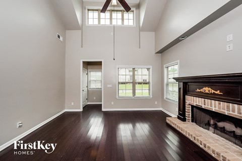 A spacious living room with a fireplace and a view of the backyard through the window.