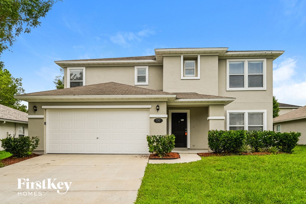 a beige house with a garage door and a lawn