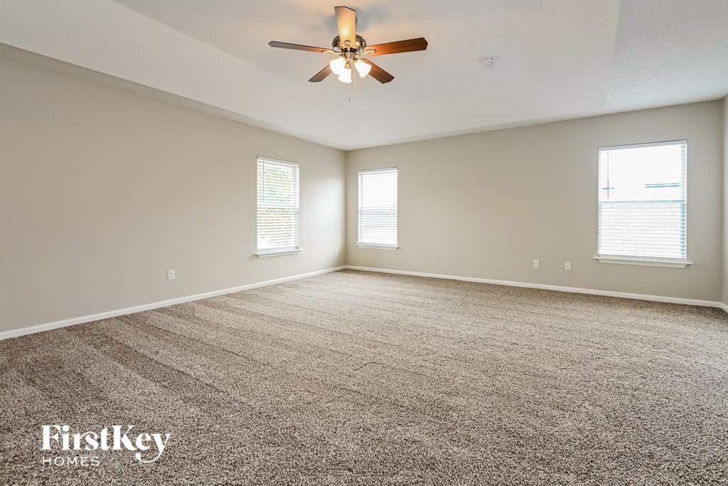 an empty living room with a ceiling fan