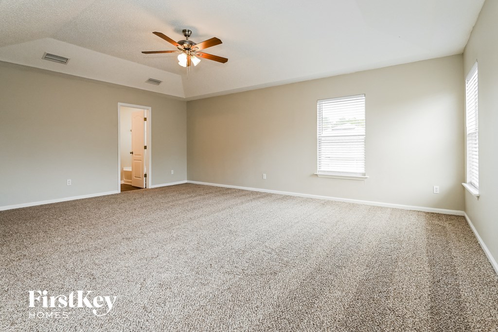 an empty living room with carpet and a ceiling fan