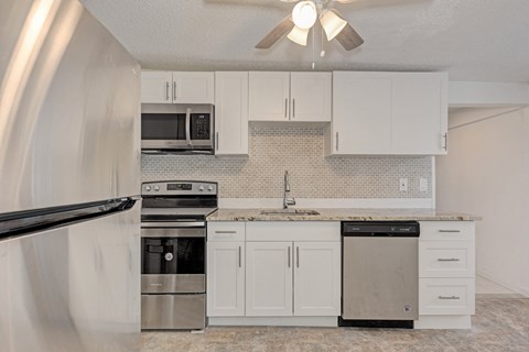 A kitchen with white cabinets and a marble countertop.