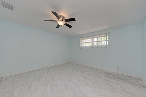 A room with a ceiling fan and a window with blinds.