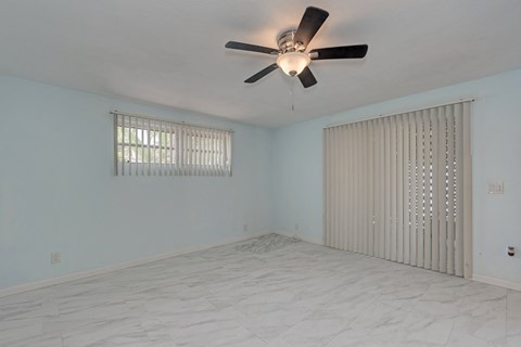 A room with a ceiling fan and a window with blinds.