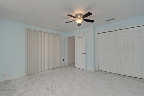 A room with a ceiling fan and three doors.