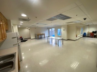A large, empty room with a kitchen area on the left side.