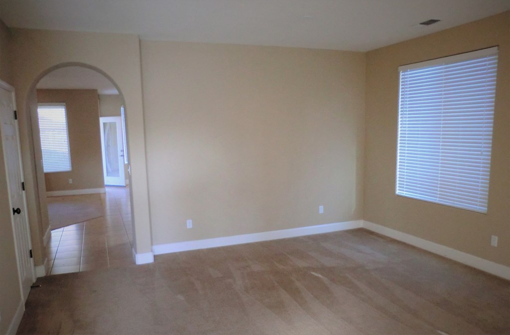 an empty living room with wooden floors and a large window