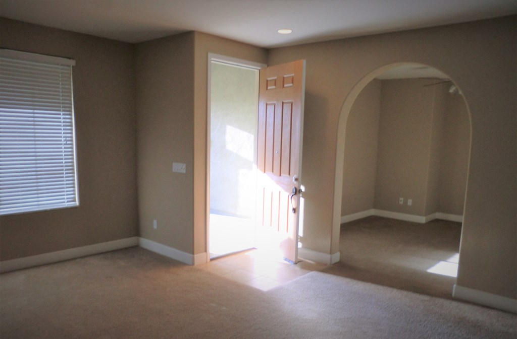 an empty living room with a door to a hallway and a door into a room