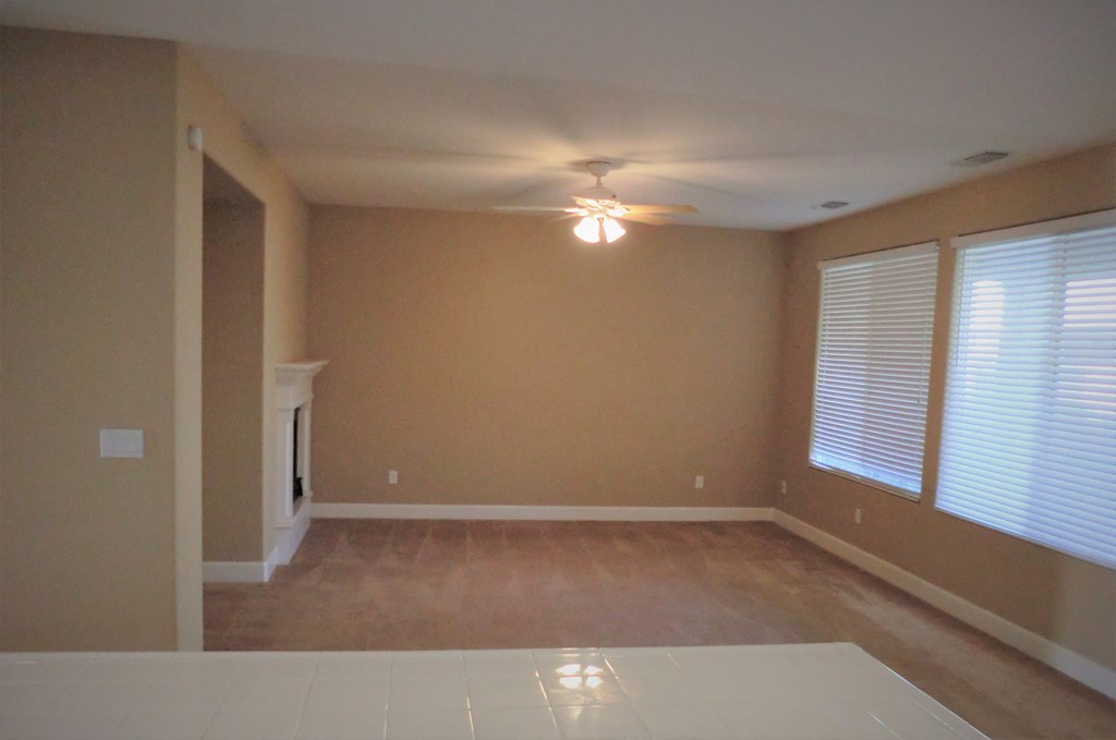 an empty living room with a ceiling fan and a window