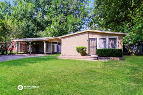 a small tan house with a yard and a gate