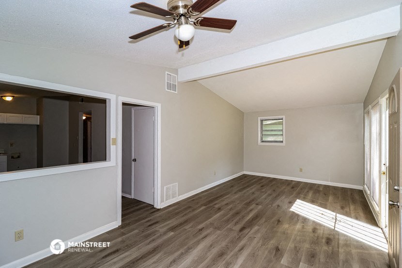 the living room of an empty house with a ceiling fan