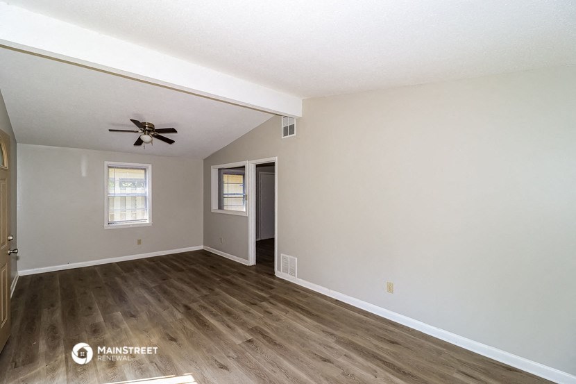 the living room of an empty house with a ceiling fan