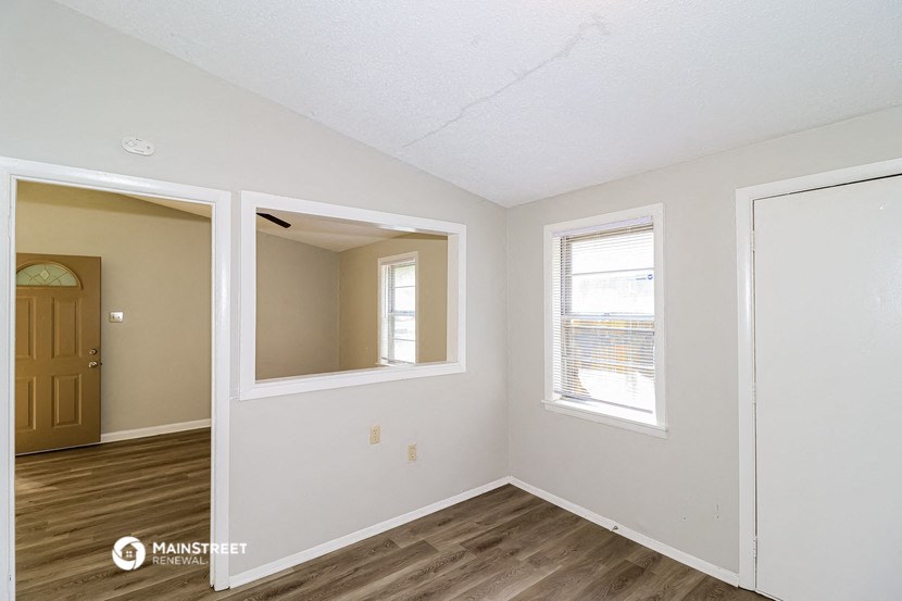 the living room of an empty house with a door and a window