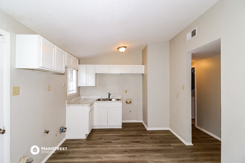 an empty kitchen with white cabinets and a white counter top
