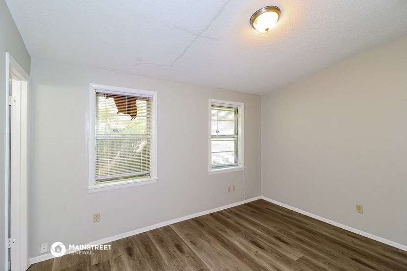 the spacious living room with hardwood flooring and two windows