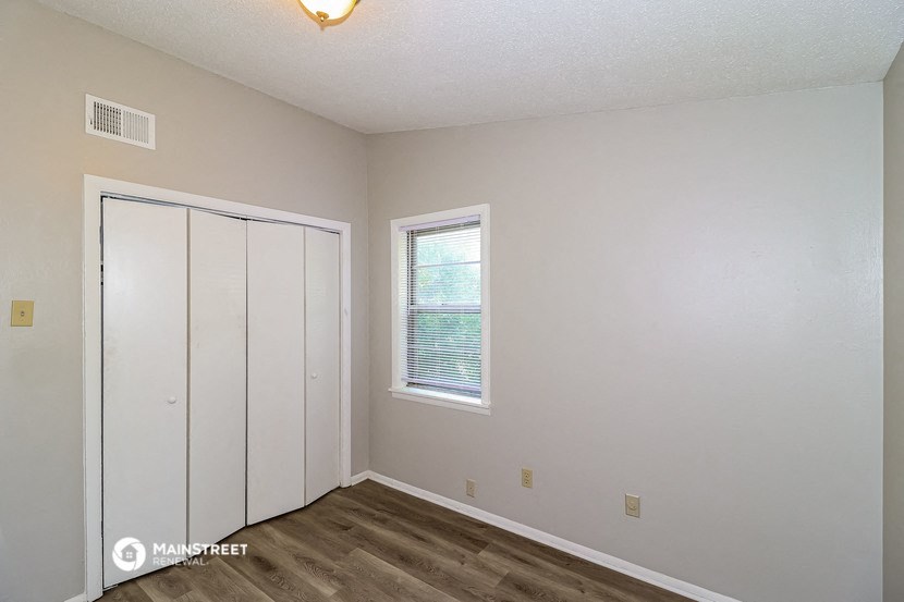 the bedroom of an apartment with a closet and a window