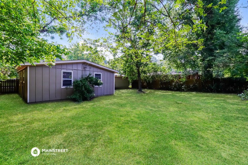 a small pink shed in the backyard of a backyard with trees