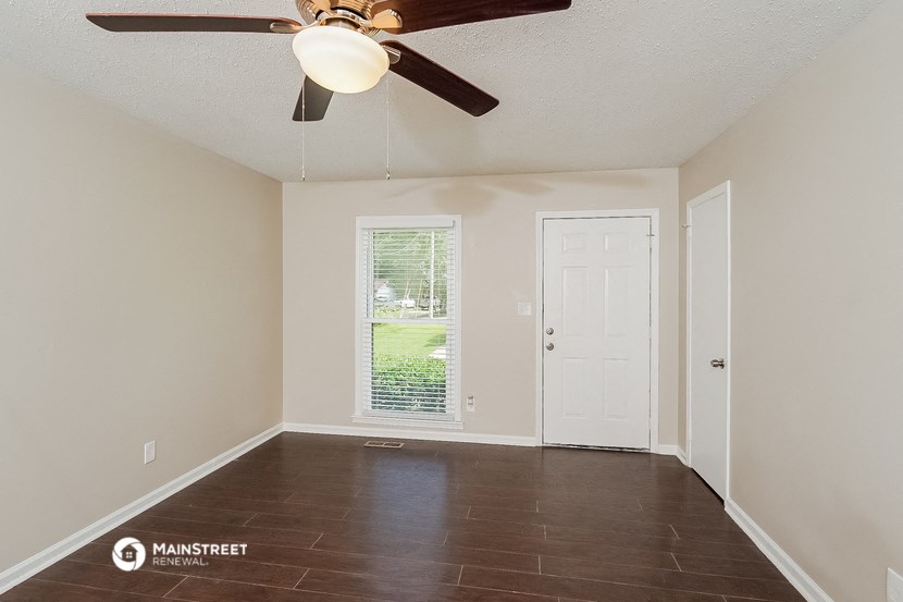 a empty living room with a ceiling fan and a door